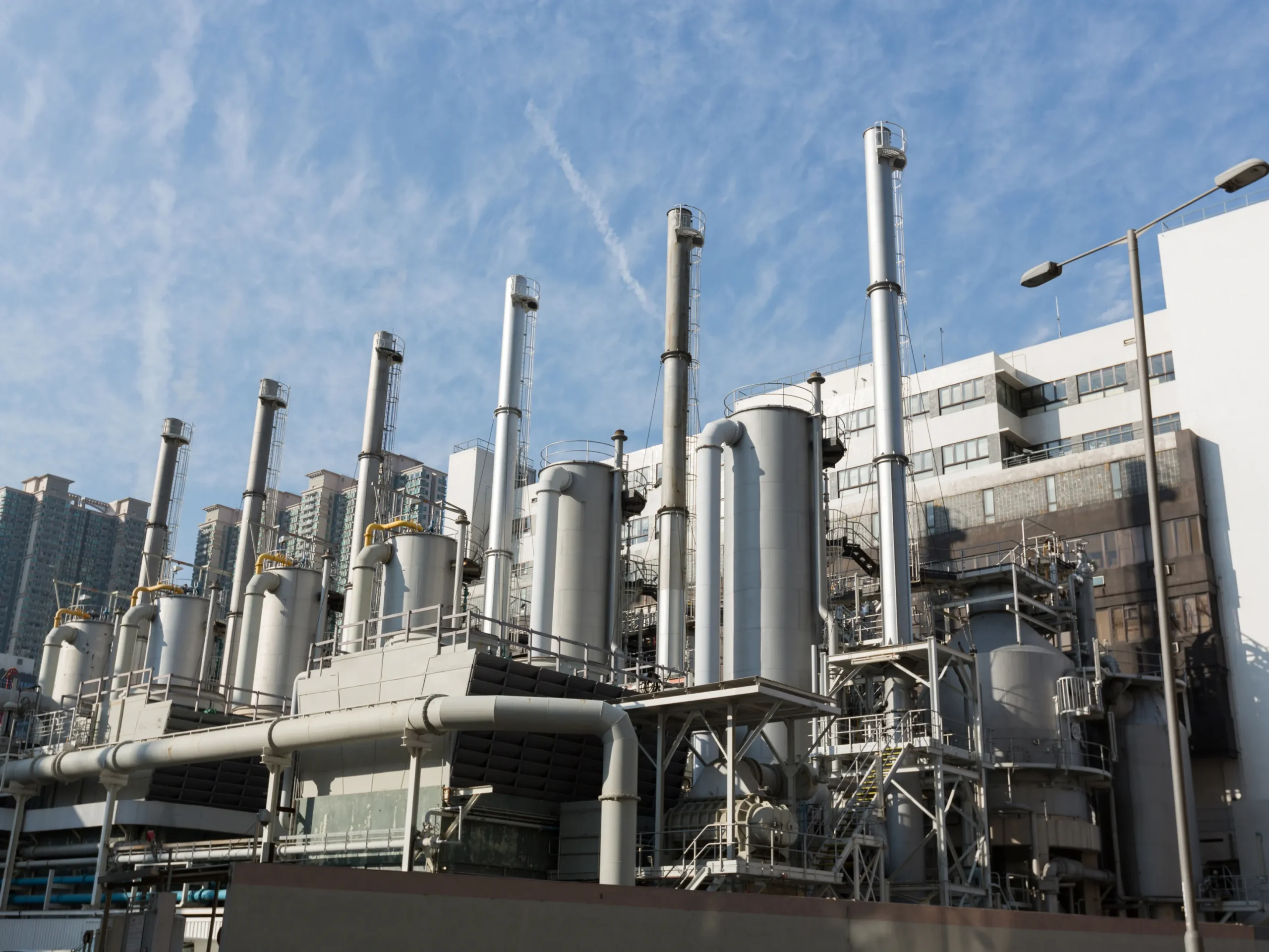 A factory sits under a blue sky smattered with wispy clouds.