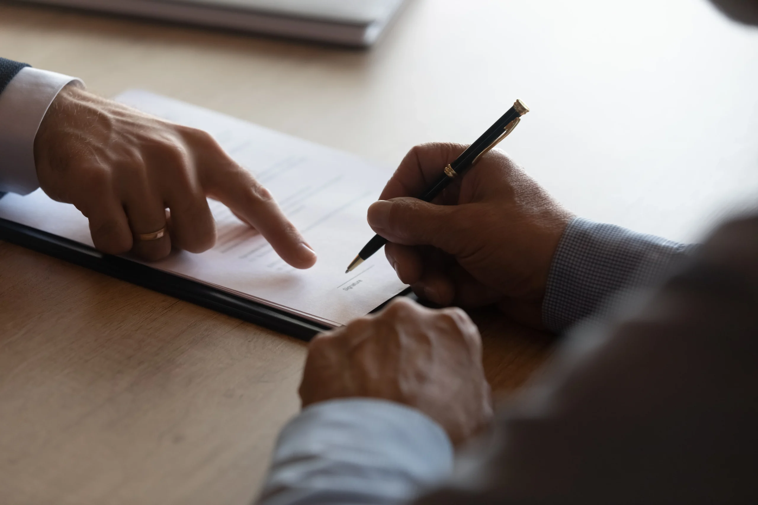 A lawyer shows their client where to sign a contract.