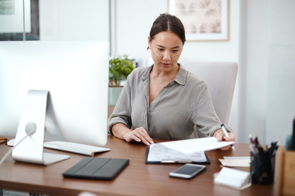 A focused woman looks through the pages of a report. She’s able to navigate the document because the writer followed our report writing advice.