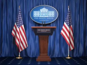 A White House podium flanked by two United States flags.