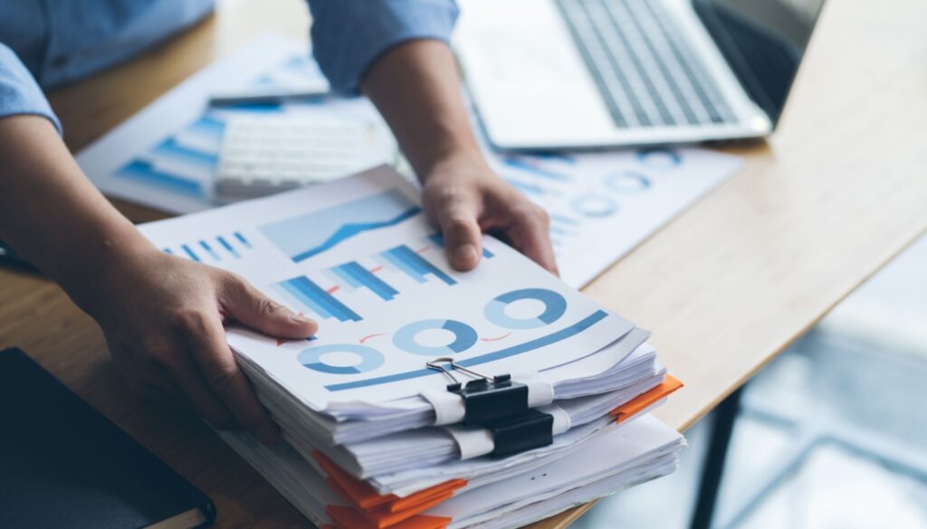 Two hands hold a thick stack of reports.