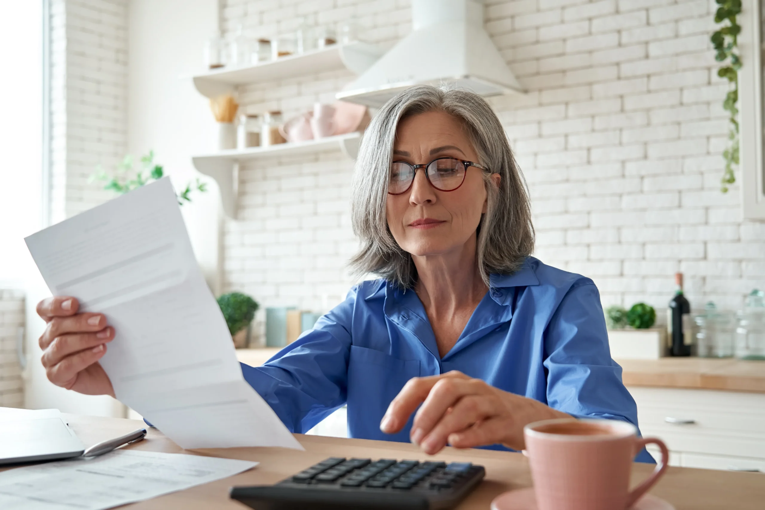 Woman with grey hair reads a letter.