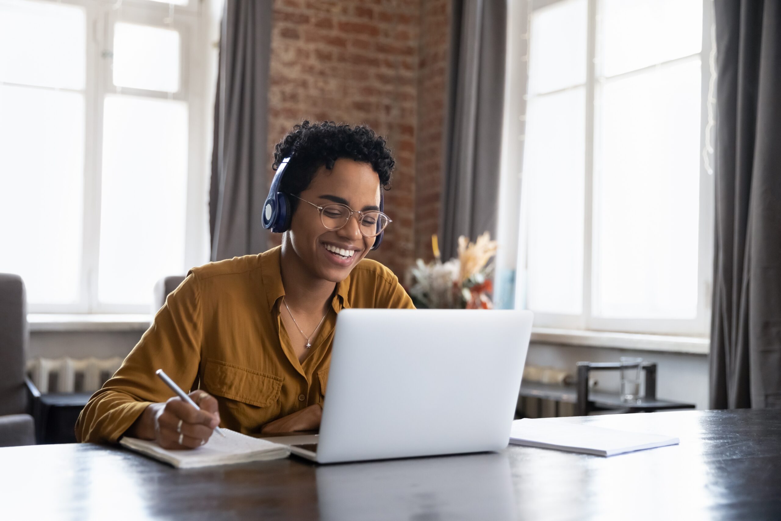 A smiling professional takes notes during a webinar.